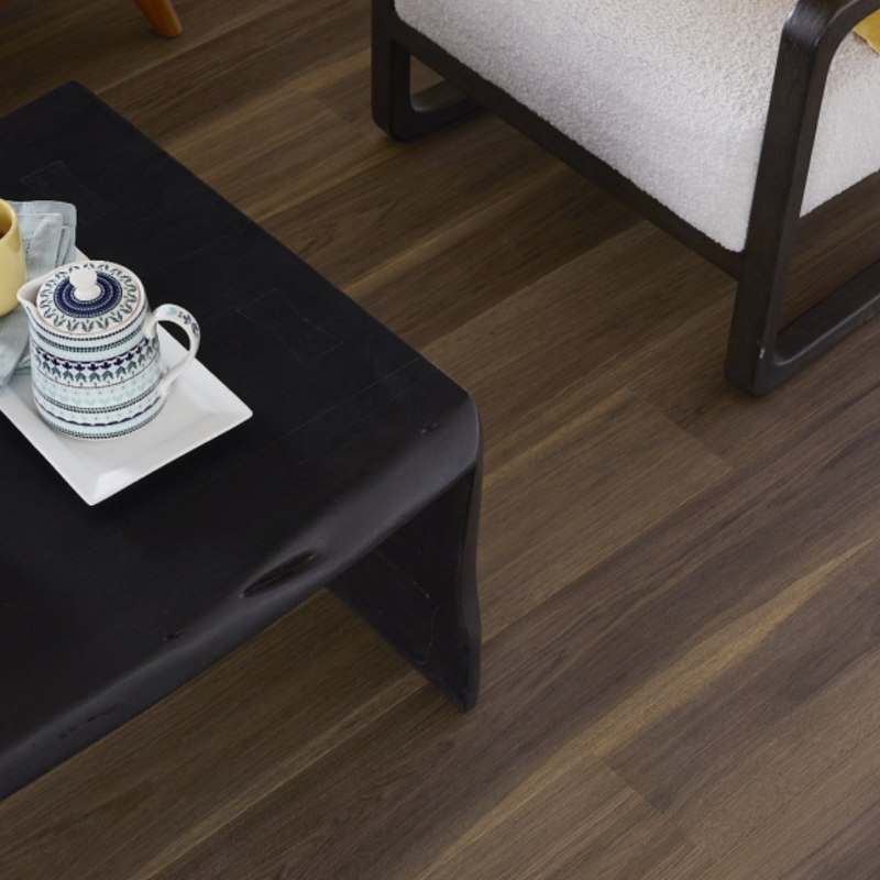 Dark Pergo flooring in a seating area with a black coffee table and white chair